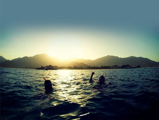 solnedgang over bjerge i vand