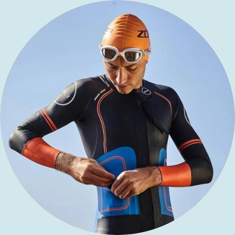 Mand som rør højre side af sin torso med våddragt på.